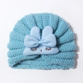 Detailed close-up of sky blue knitted baby hat with soft bunny ears and cute embroidery - Blue