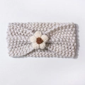 Detailed macro view of cream knitted baby headband with a handcrafted crochet flower - Beige