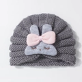 Close-up of cute grey knitted baby hat with rabbit design and pink bow detail - Gray