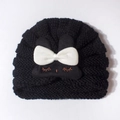 Close-up of baby knit hat with 3D white bow and embroidered sleeping eyes detail - Black
