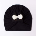 Detail of baby turban hat featuring black waffle texture and a large white bow with eyelashes - Black