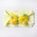 Detailaufnahme des gelben Baby-Stirnbandes mit bunten Pompons in der Netzschleife - Beige