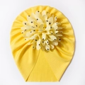 Detail eines gelben Baby-Turbans mit gerippter Struktur und 3D-Blume mit schwarzen Punkten - Gelb