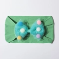Detail of mint green baby headband with mesh bow filled with colorful pom-poms - Green