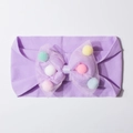 Detailed view of purple baby headband featuring a mesh bow filled with colorful pom-poms - Purple