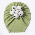 Close-up of ribbed green baby turban hat featuring a large white polka dot fabric flower - Green