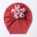 Detail shot of the brick red ribbed baby turban hat with a pink polka dot fabric flower - Wine Red