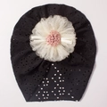 Detail of baby lace turban hat featuring a black mesh fabric and a large handmade flower - Black