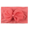 Gros plan d'un bandeau pour bébé rose corail avec un nœud en mousseline sur fond blanc - Rouge pastèque