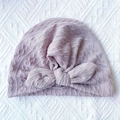 Detailed texture of baby knitted beanie with large bow decoration on ribbed fabric - Gray