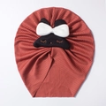 Detail of baby ribbed turban hat in rust red with cute black cat patch and white bow - Wine Red