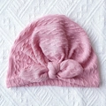 Detail of pink ribbed baby turban hat with large bow and cable knit texture - Nude Pink
