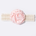 Dettaglio di una rosa di raso rosa su una morbida fascia in pizzo bianco per neonati - Gemma di Neve