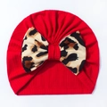 Close-up of baby beanie featuring red ribbed knit fabric and a leopard print bow - Red