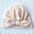 Detail of soft apricot ribbed knit baby turban hat with a large bow decoration - Beige