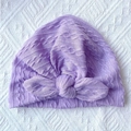 Detail of lilac knitted baby hat with ribbed texture and decorative bow on white background - Purple