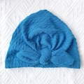 Close-up of peacock blue baby turban hat with soft cable knit texture and large bow detail - Sapphire Blue