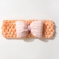 Détail macro du bandeau élastique orange ajouré avec nœud à carreaux rose et blanc - Bourgeon de Neige