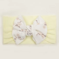Close-up of baby nylon headband with large white ribbed bow featuring floral patterns - Beige