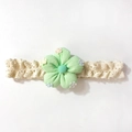Détail d'un bandeau en dentelle pour bébé avec fleur en tissu vert menthe et broderies - Vert