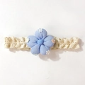 Détail d'un bandeau bébé avec broderie florale bleu clair sur un tissu en dentelle beige - Bleu