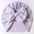 Detail der lila Babymütze mit Jacquard-Textur und einer großen dekorativen Schleife - Lila