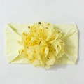 Détail d'un bandeau bébé jaune pâle avec ornement floral à pois dorés scintillants - Beige