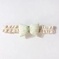 Dettaglio fascia neonato in pizzo con fiocco a quadretti verde chiaro su sfondo bianco - verde chiaro