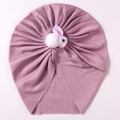 Dettaglio di un berretto a coste per neonati con un coniglio di peluche bianco su fondo rosa - Viola Taro