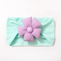 Détail d'un bandeau bébé en tricot vert menthe avec une grande fleur en tissu mauve - Vert menthe