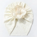 Detalle de turbante para bebé en tejido calado con una gran flor decorada con perlas - Beige