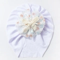 Close-up of white ribbed baby turban hat with floral lace flower and woven bow detail - White