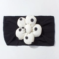 Detail of baby headband featuring black ribbed knit fabric and large white polka dot flower - Black