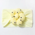 Detail of soft knitted yellow baby headband featuring a large floral daisy pattern - Beige