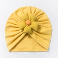 Detailed texture of yellow knitted baby hat with a prominent decorative orange fabric flower - Yellow