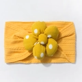 Detail of yellow knitted baby headband featuring a large polka dot 3D flower decoration - Yellow