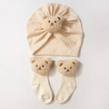 Close-up of beige baby hat and socks set featuring 3D plush bear ears on soft knit fabric - Beige