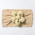 Macro detail of knitted baby headband with a large polka dot 3D flower decoration - Light Coffee