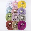 Vue à plat de 12 couleurs de turbans bébé en tricot côtelé doux avec décor yeux mignons - 12 Couleurs Mélangées