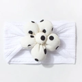 Detail of soft white baby headband featuring a 3D floral accent with black polka dots - White