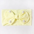 Dettaglio della fascia per neonati in maglia a coste giallo chiaro con fiocco e perle - Beige