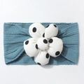 Detail of blue ribbed knit baby headband featuring a large white polka dot floral ornament - Navy Blue