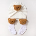 White knit baby hat and socks set featuring a cute plush brown bear decoration - White