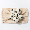 Detail view of beige knitted baby headband with a large black heart pattern floral accent - Beige Coffee