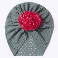 Détail du bonnet en dentelle ajourée pour bébé avec une grande rose rouge dessus - Vert clair