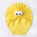 Detailed view of yellow ribbed fabric texture and funny plush eyes on a baby cap - Yellow