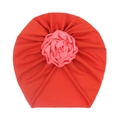 Detail view of baby turban hat with a red knit base and a soft pink satin rose decoration - Orange