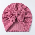 Close-up of ribbed rose pink newborn hat with large decorative bow on white background - Brick Red
