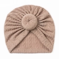 Detail of baby turban hat featuring light camel cable knit texture and donut knot - Coffee