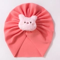 Close-up of pink knit baby turban hat with a plush pig character and ribbed texture - Nude Pink